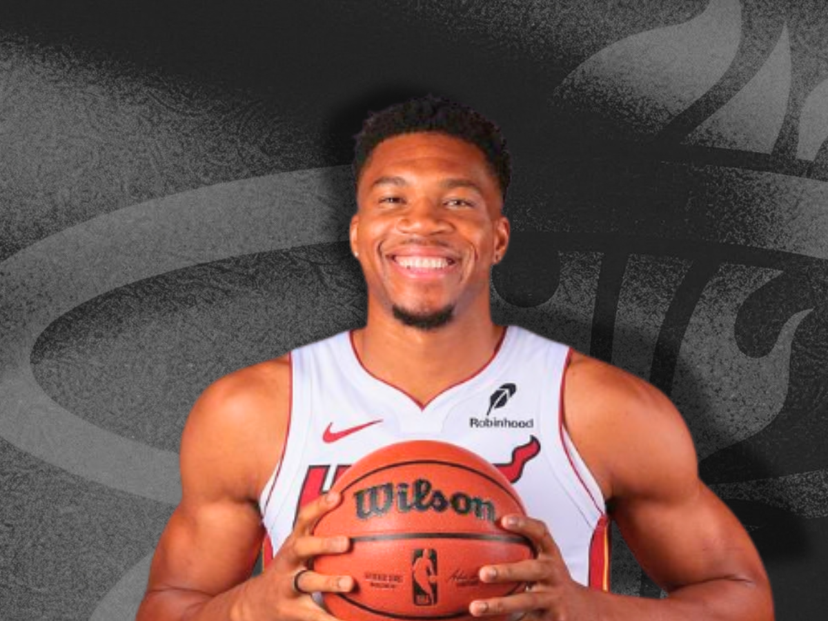 Giannis Antetokounmpo smiling in a Miami Heat jersey holding an official NBA basketball ahead of the Giannis Antetokounmpo Heat debut.